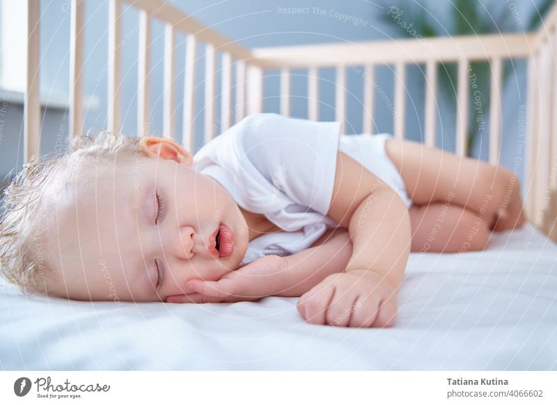 Baby schläft in Baby Holzbett für Neugeborene. Ein geräumiges, helles Zimmer mit einer Dattelpalme im Hintergrund. Raum kopieren Kleinkind Säugling Bett