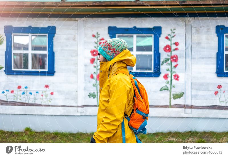 Reisender Mann vor einem traditionellen Holzhaus, Polen kalt Winter Rucksack Backpacker Tourist jung ländlich Volkskunst Sehenswürdigkeit polnisch