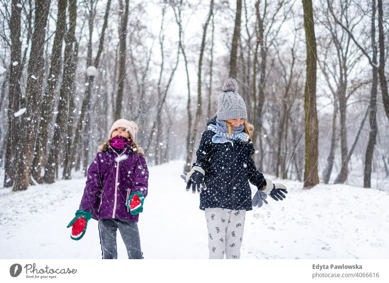 Kinder werfen Schnee in die Luft und genießen einen kalten Wintertag Werfen Tochter zwei Lachen Freunde Genuss Aktivität spielerisch genießend spielen Lächeln