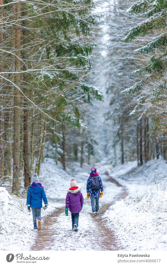 Mutter und Kinder genießen einen gemeinsamen Winterspaziergang durch den Wald im Freien Zusammensein Familie Abenteuer aktiv Tourist Mädchen Frau Aktivität
