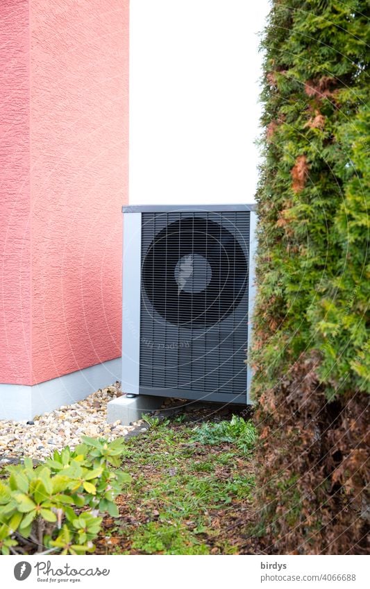 Luftwärmepumpe im Vorgarten eines Wohnhauses. Luftwasserwärmepumpe Hausecke Luft-Wasser-Wärmepumpe Umweltschutz Heizungsergänzung Ventilatoren Pflanzen