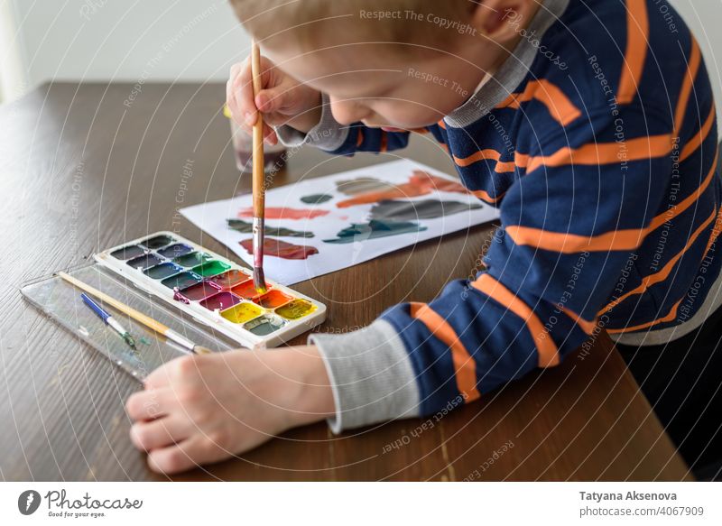 Kleiner Junge malt mit Aquarellfarbe Kind Zeichnung Künstler Hobby Farbe Pinselblume Wasserfarbe Kunst Anstreicher Kreativität Person Bürste Hand Papier Malerei