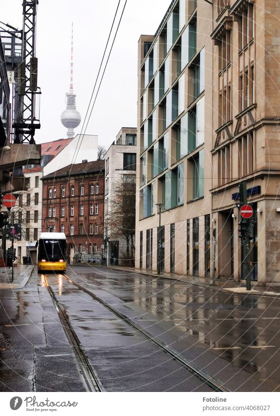 Berlin von seiner grauen Seite. Auch der Fernsehturm versteckt sich im Grau in Grau. Nur die Straßenbahn leuchtet knall gelb. Außenaufnahme Farbfoto Hauptstadt
