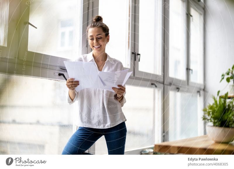 Junge Geschäftsfrau schaut auf Papierkram in einem Büro Jahrtausende Schüler Hipster im Innenbereich Loft Fenster natürlich Mädchen Erwachsener attraktiv
