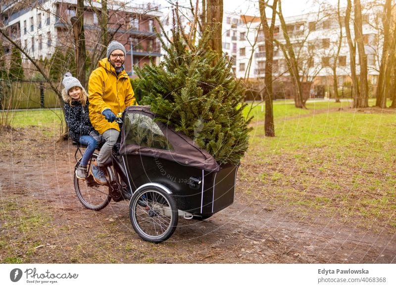 Vater und Tochter haben eine Fahrt mit Fracht Fahrrad transportieren Weihnachtsbaum nachhaltiger Transport Baum Spaß Freude genießend Hipster modern