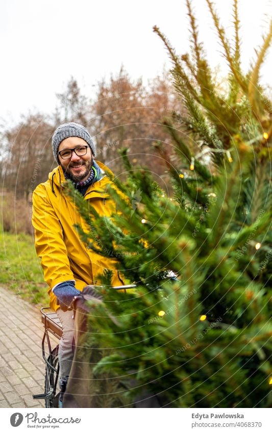 Mann transportiert Weihnachtsbaum auf Fahrrad nachhaltiger Transport Baum Spaß Freude genießend Hipster modern transportierend tragen tausendjährig Winter