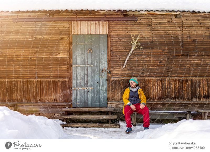 Mann sitzt vor einem traditionellen Holzhaus Gesunder Lebensstil ökologisch altehrwürdig Landhaus Fernweh Totholz Cottage Wälder Gebäude rustikal heimwärts