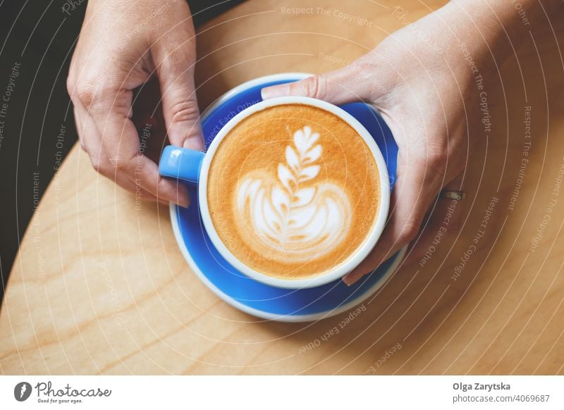 Die Hand einer Frau hält einen Kaffee mit Latte Art. Kunst Cappuccino Tasse Becher Hintergrund Person altehrwürdig weiß Café trinken Espresso heiß Top Getränk