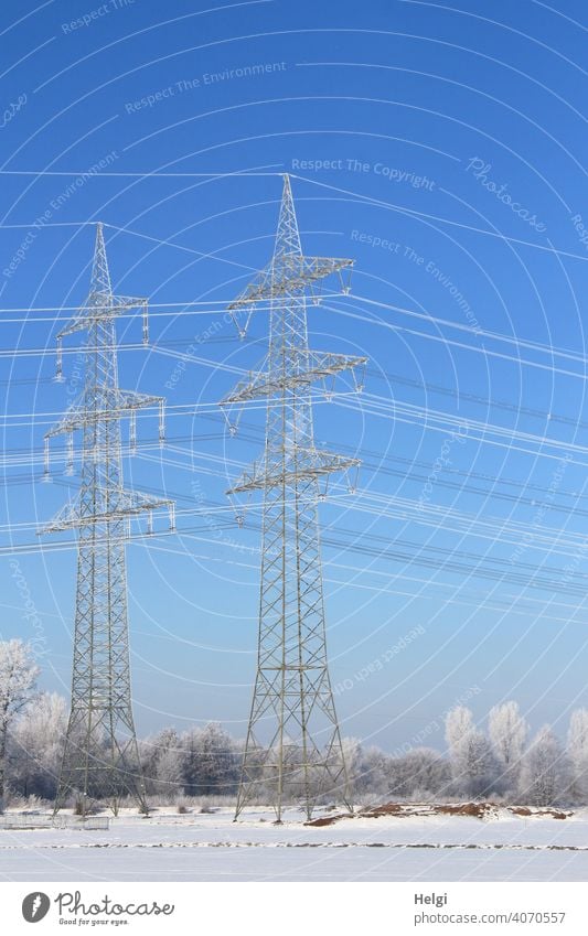 riesige Strommasten mit Raureif bedeckt in winterlicher Landschaft mit blauem Himmel zwei Hochspannungsmast Stromversorgung Energieversorgung CO2 Elektrizität