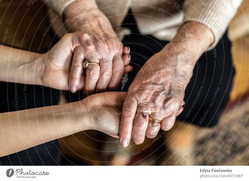 Ausgeschnittene Aufnahme einer älteren Frau, die mit einer Krankenschwester Händchen hält Hände tröstlich Händchenhalten knittern echte Menschen offen Senior