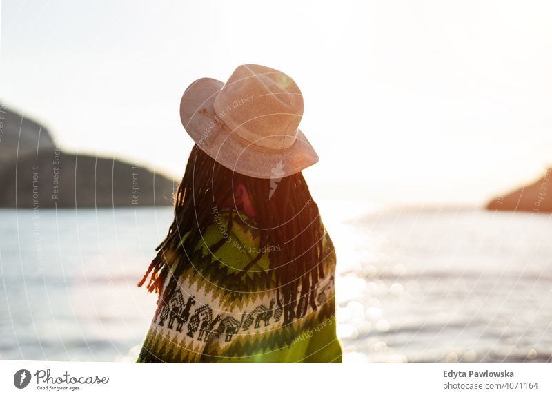 Junge Frau mit einem Hut am Strand bei Sonnenuntergang reisen Tourist Tourismus Urlaub Backpacker schön attraktiv jung Erwachsener Menschen im Freien lässig