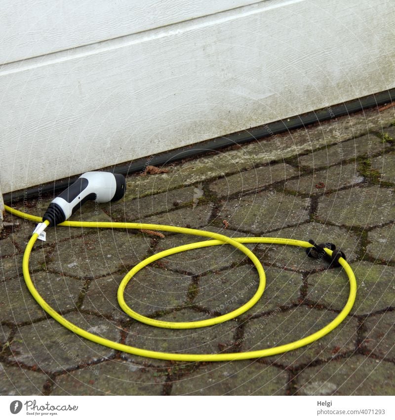 gelbes Ladekabel mit Stecker liegt vor einer Garage und wartes auf das  Elektroauto - ein lizenzfreies Stock Foto von Photocase