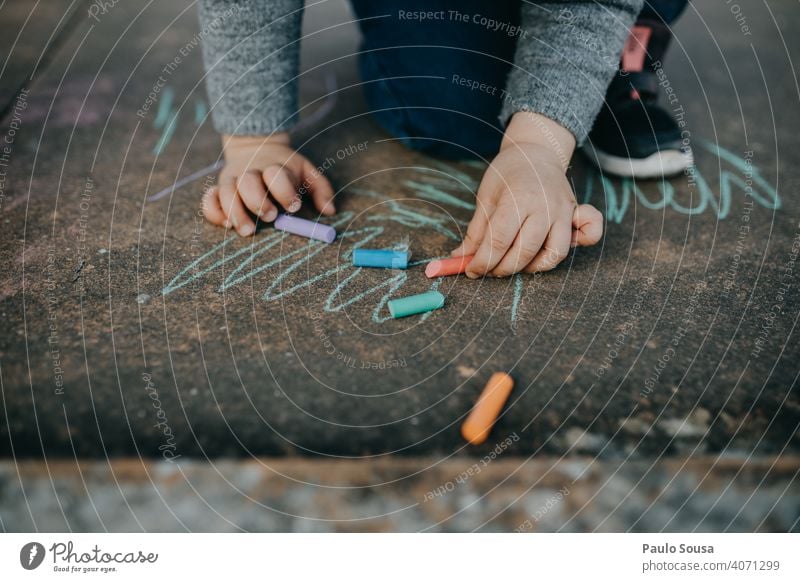 Kind zeichnet mit farbiger Kreide auf dem Boden zeichnen Zeichnung Strassenmalerei Kreidezeichnung Spielen Kindheit Kreativität malen Straße Kunst Kinderspiel