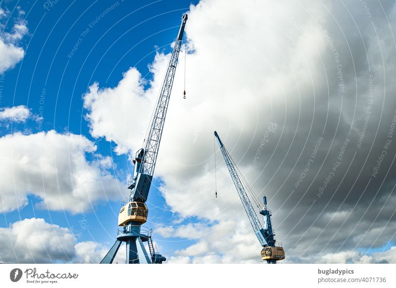 Zwei blau-gelbe Kräne vor wolkigem Himmel in einem Hafen Kran Krane Ladekran Blauer Himmel Wolken Wolkenhimmel Baustelle Bauarbeiten Industrie Hafenkran