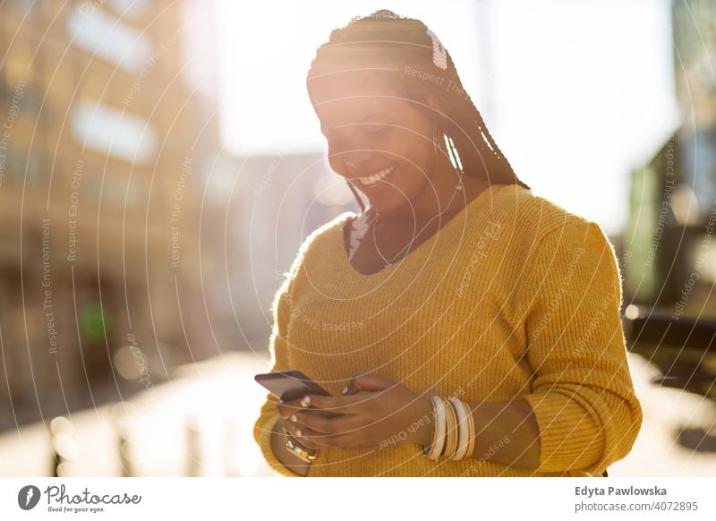 Junge Frau mit Smartphone in einer städtischen Umgebung eine Person allein im Freien Tag Positivität selbstbewusst sorgenfrei Menschen jung Erwachsener lässig