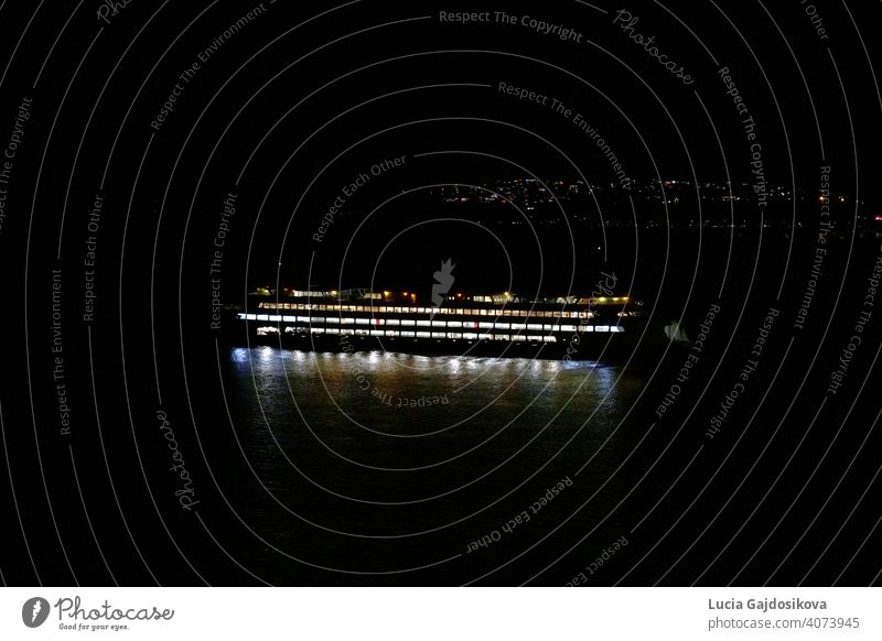 Die Seattle-Bainbridge-Fähre beleuchtet von Kabine und Navigationslichter ist in der Nacht zwischen Seattle und Bainbridge Island, Washington über Puget Sound vorbei. Im Hintergrund sind Lichter der Vororte von Seattle mit viel Kopierraum.