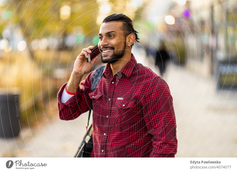Hübscher junger Mann mit Handy auf der Straße Singhalesisch asiatisch Inder bärtig außerhalb urban Stehen im Freien Großstadt Warschau eine lässig Lifestyle Typ