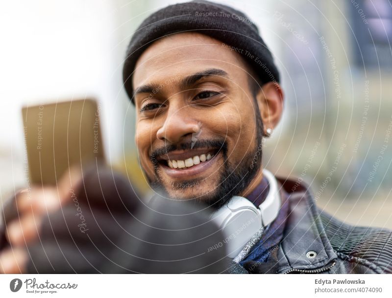 Hübscher junger Mann mit Handy auf der Straße Singhalesisch asiatisch Inder bärtig außerhalb urban Stehen im Freien Großstadt Warschau eine lässig Lifestyle Typ