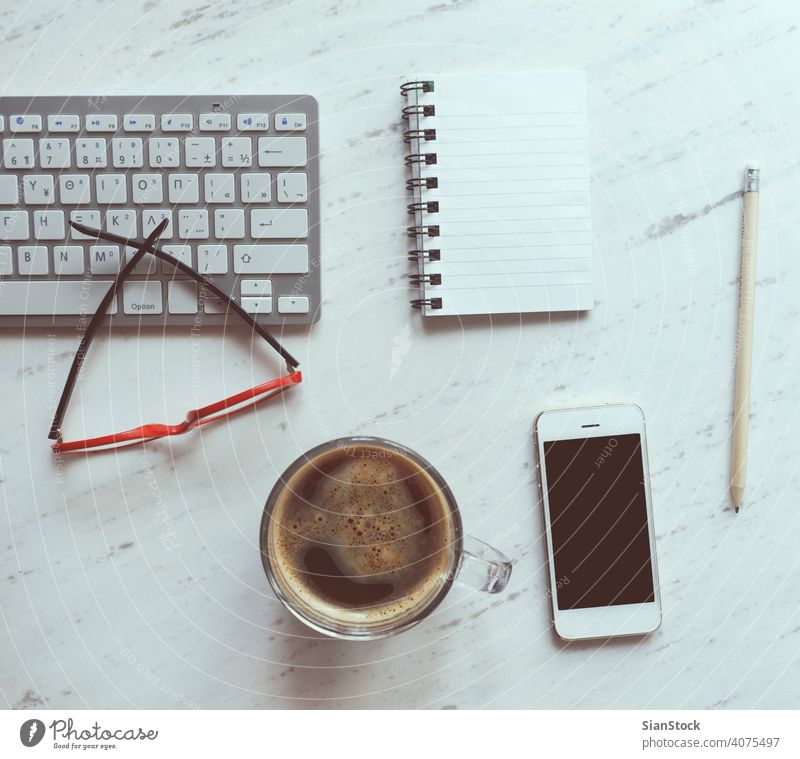 Arbeitsplatz mit Notebook, Kaffee, Smartphone, Brille und Tastatur. Laptop Top Schreibtisch Ansicht Tisch Büro Computer Tasse Desktop weiß Keyboard oben