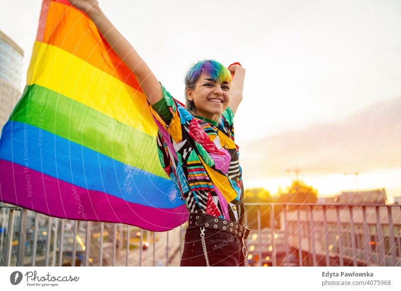 Porträt einer glücklichen nicht-binären Person, die eine Regenbogenflagge schwenkt geschlechtsfluid Gender-Fluidität lgbt Gleichstellung Homosexualität lesbisch