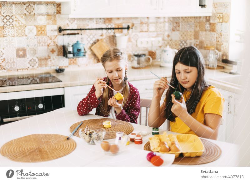 Zwei Schwestern sitzen am Tisch und malen Ostereier in verschiedenen Farben für Ostern Frühling Kind Feiertag Vorbereitung Ei hell Familie Mädchen weiß