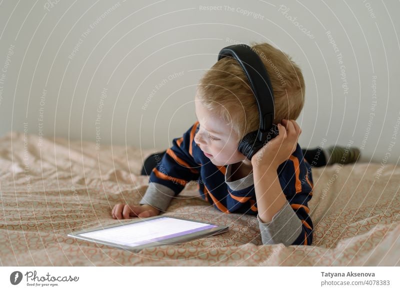 Junge mit Tablette auf dem Bett Kind Internet Technik & Technologie Lernen modern heimwärts digital Freizeit Bildung digitales Tablett Mitteilung Kindheit