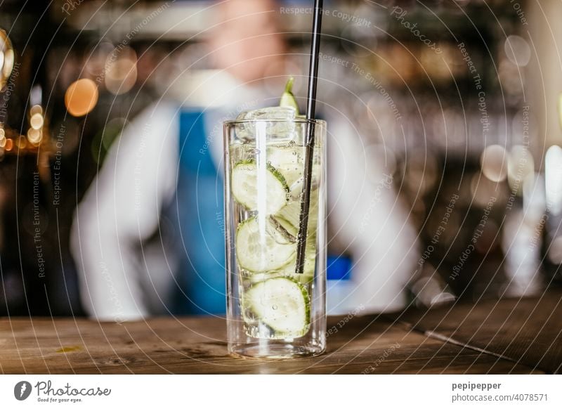 Cocktail mit Barkeeper im Hintergrund Cocktailbar Cocktailglas Gurke lemon Glas Getränk Longdrink Alkohol Spirituosen Erfrischungsgetränk Nachtleben