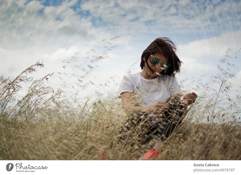 Frau im Gras sitzend, Haare im Wind wehend, in einem Zustand der Entspannung. Erwachsener schön Schönheit Wald Frisur Lifestyle natürlich Natur außerhalb