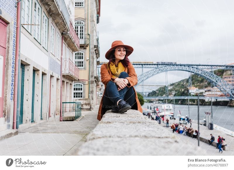 junge schöne Frau sitzt am Fluss bei Sonnenuntergang und genießt die Aussicht auf Porto. Reisen Konzept reisen Großstadt Sightseeing urban Kaukasier Menschen