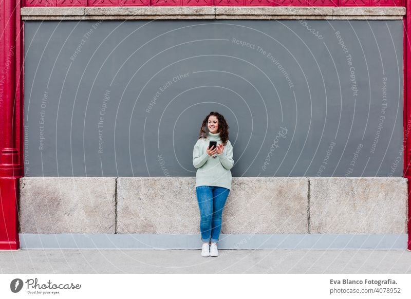 Junge kaukasische Frau, die ein Mobiltelefon im Freien in der Stadt benutzt. Technologie und Lebensstil Handy Großstadt urban Technik & Technologie Texten