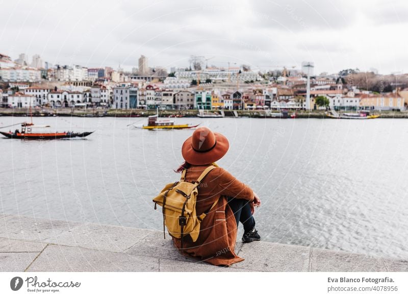 Rückenansicht der jungen schönen Frau sitzt am Fluss bei Sonnenuntergang genießen Porto Ansichten. Reisen Konzept reisen Großstadt Sightseeing urban Kaukasier