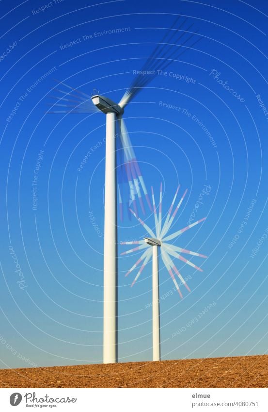 Zwei Windräder - Mehrfachbelichtung - auf einem Acker und vor blauem, wolkenlosen Himmel / alternative Stromerzeugung / Windkraft Windrad Drehung drehen Rotor
