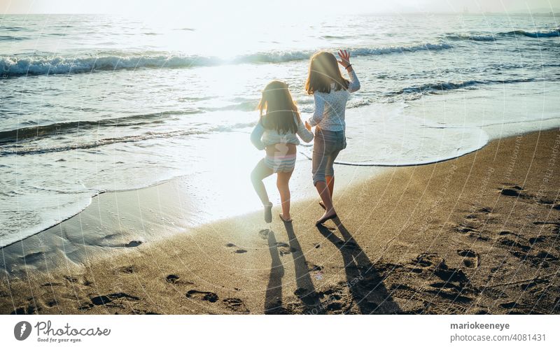 Rückenansicht von zwei kleinen Mädchen, die sich an einem sonnigen Nachmittag vor dem Meer an den Händen halten. Konzept der Freundschaft Zwei Personen