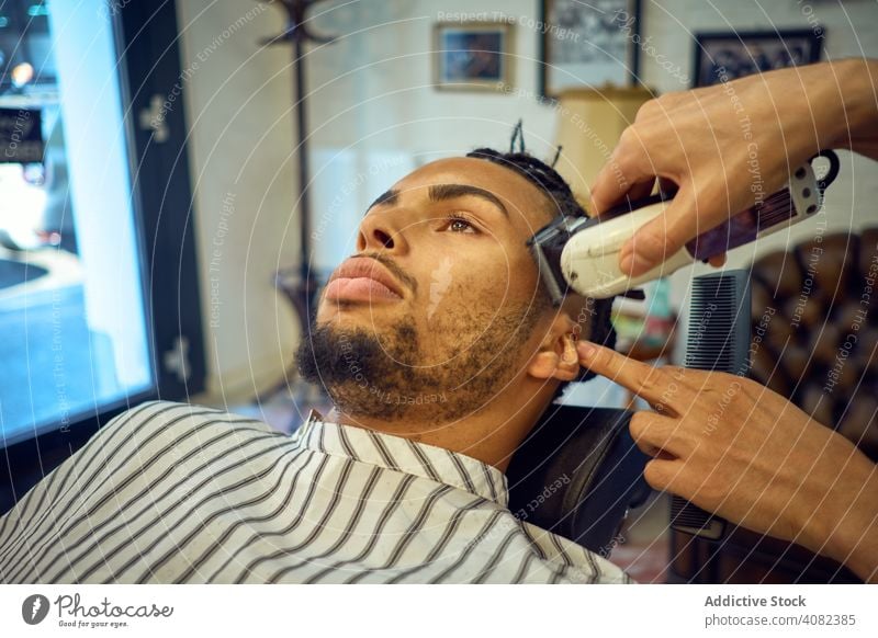 Anonymer Hairstylist beim Haarschnitt Friseur Kunde Pflege Friseursalon Trimmen Rasierer Mann Gesicht Behaarung Stil Spiegel Salon schwarz Afroamerikaner jung