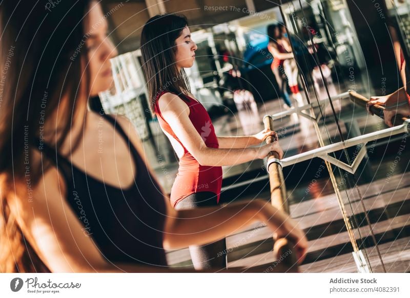 Junge Balletttänzerin trainiert im Studio Frauen Stange strecken Tänzerinnen Lektion Spiegel Tanzen Training selbstbewusst Sonnenlicht emotionslos sportlich