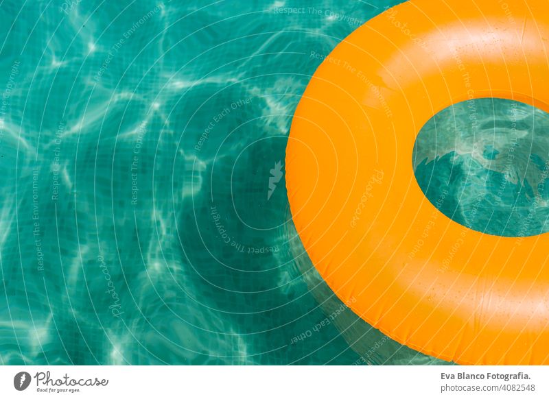 orange aufblasbaren Donut auf blauem Wasser in einem Schwimmbad. Sommer Spaß Pool Krapfen Party Sommerzeit schön Schwimmer Schwimmsport Frau Freizeit