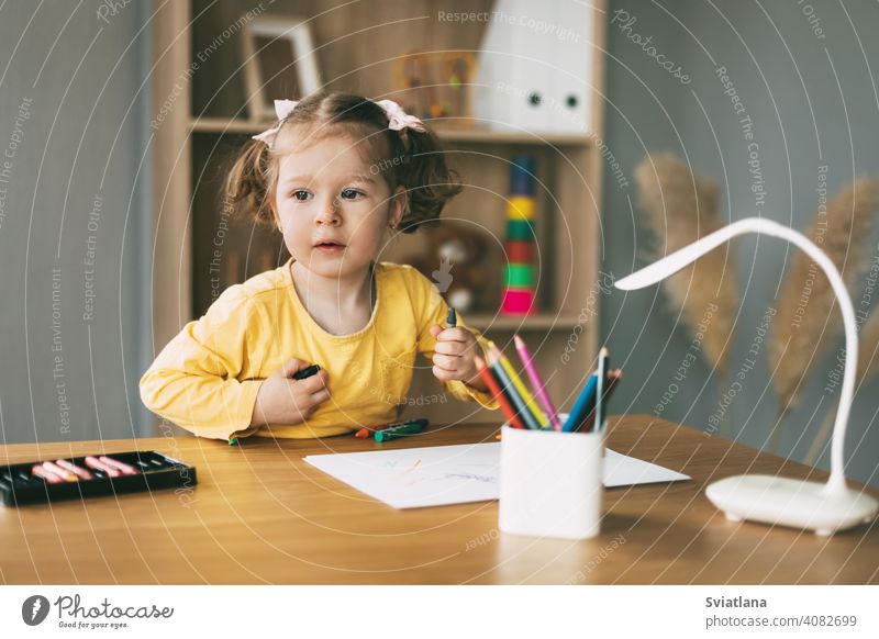 Ein kleines Mädchen zeichnet am Tisch mit Buntstiften zu Hause oder im Kindergarten. Kindheit, Kreativität, Bildung. zeichnen wenig Bleistift Papier niedlich