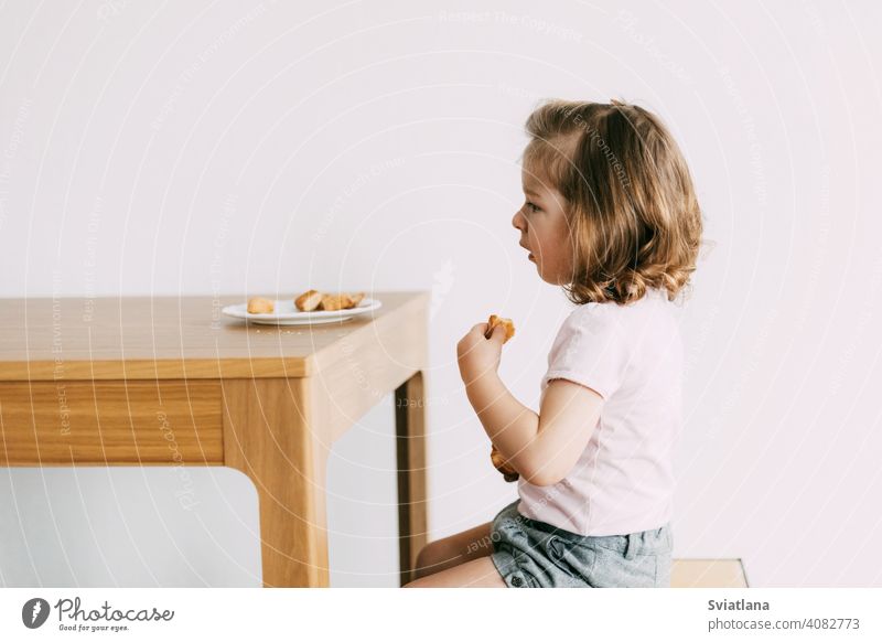 Ein kleines Mädchen sitzt an einem Tisch und isst Kekse wenig Kind Glück Ernährung Lebensmittel jung Kindheit niedlich Küche Gesicht Menschen essen Gesundheit