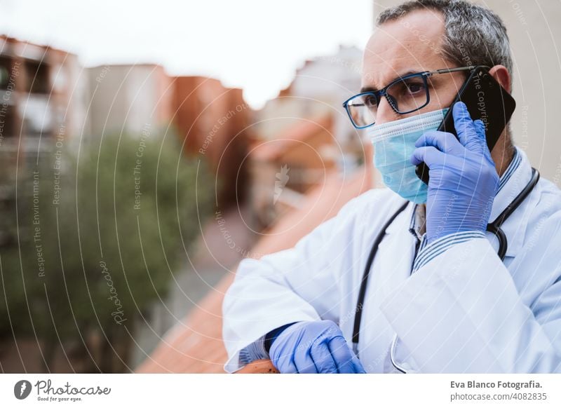 Arzt Mann eine Pause machen, mit Handy. Das Tragen von Schutzhandschuhen, Maske und Stethoskop. coronavirus covid-19 Konzept Corna-Virus Schutzmaske Porträt