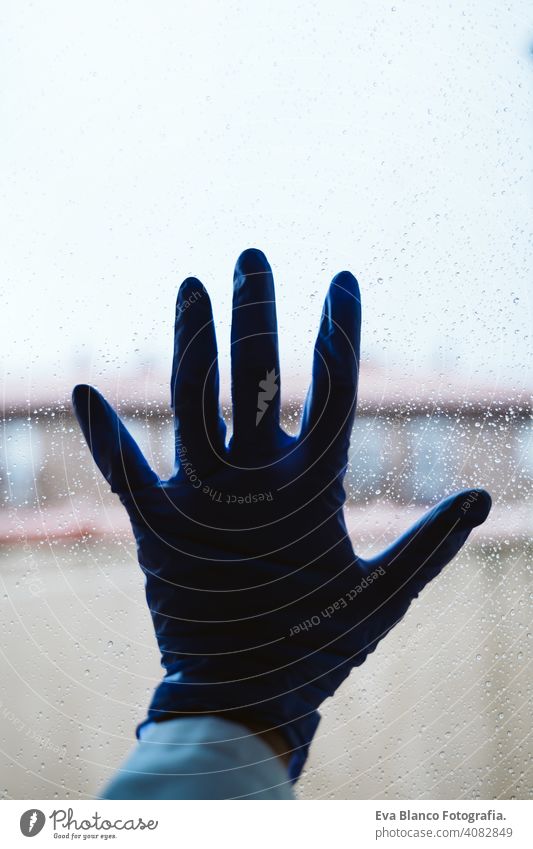 Hand eines Arztes an einem Fenster, regnerischer Tag. Coronavirus covid-19 Konzept professionell Corona-Virus Krankenhaus arbeiten Infektion Handschuh tragend