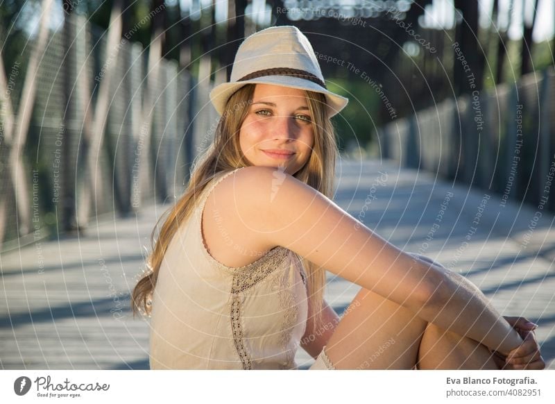 Porträt einer jungen Frau bei Sonnenuntergang im Freien Glück blond Hut blaue Augen Brücke Sommer sonnig Behaarung Fröhlichkeit Lifestyle Gesicht schön Spaß