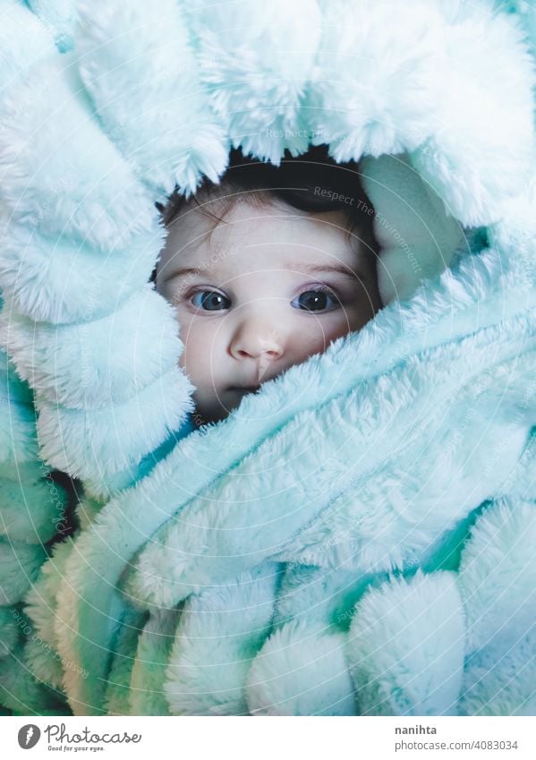 Kleines Baby eingewickelt mit einer warmen grünen Decke Porträt kleines Mädchen künstlerisch Winter gemütlich Vorleger warme Kleidung heimwärts blaue Augen