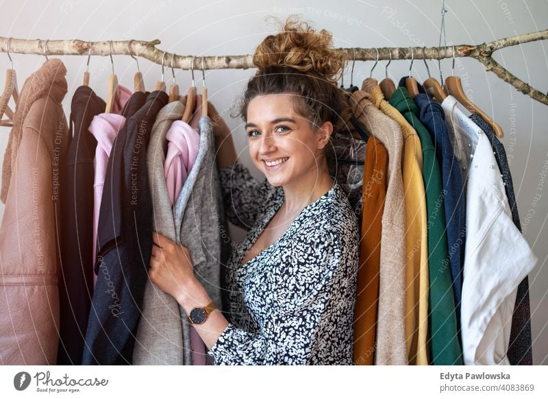 Junge Frau beim Einkaufen in einer Kleiderboutique Mode Bekleidung Kleidung modisch Ablage auserwählend Einzelhandel Laden Werkstatt Sale Kleiderbügel Kunde