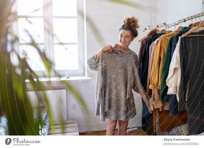 Junge Frau wählt Kleidung Mode Bekleidung modisch Ablage auserwählend Einzelhandel Laden Werkstatt Sale Kleiderbügel Kunde Stil Käufer konsumgeil Kleiderschrank