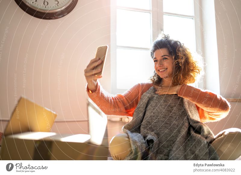 Frau, die ein Selfie macht, während sie Kleidung zu Hause anprobiert Mode Bekleidung Kasten Kollo Auspacken Verpackung kaufen online Internet Paket Karton
