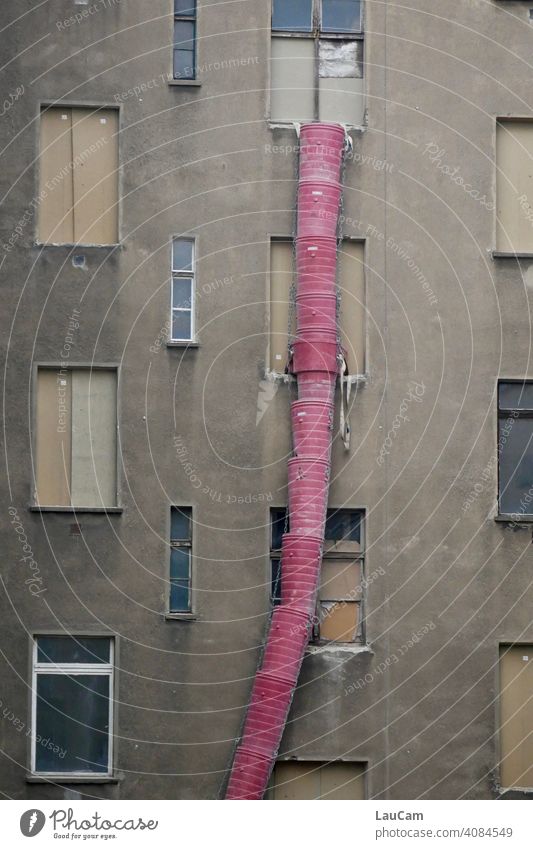 Rote Schuttrutsche vor einer grauen Hausfassade auf einer Baustelle im Prenzlauer Berg rot grau in grau Fassade Fenster Stadt urban Gebäude Gebäudefassade