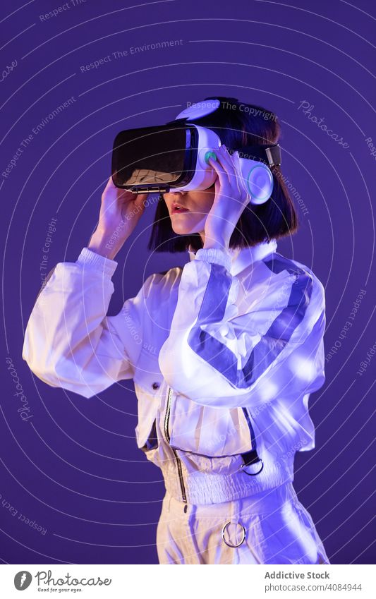 Frau im VR-Headset virtuell Realität Technik & Technologie neonfarbig Licht berührend Gerät digital Innovation jung Person Brille asiatisch modern Entertainment