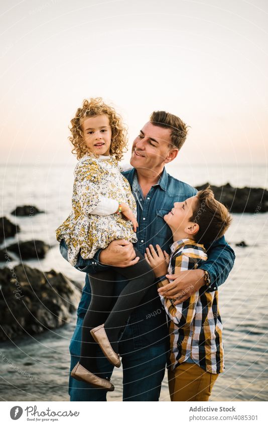 Vater mit ihren Kindern am Strand Familie Seeküste Urlaub Lächeln Umarmung umarmend Umarmen Mann mittleren Alters Tochter Sohn Mädchen