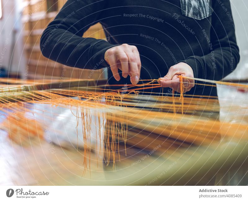 Person, die Fäden am Webstuhl hält Weber Beteiligung Gewinde Fabrik Baumwolle industriell Handwerk Textil Weberei Garn Bekleidung Gewebe traditionell Sehne
