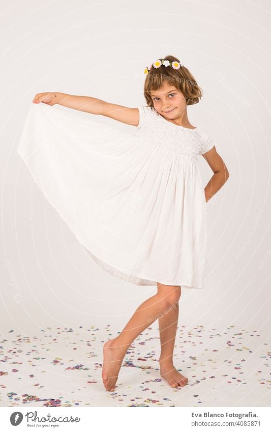 Indoor-Porträt eines Kindes Spaß haben. Konfetti auf dem Boden. weißes Kleid auf kleines Mädchen Porträt. drinnen, Konfetti auf dem Boden. weißer Hintergrund